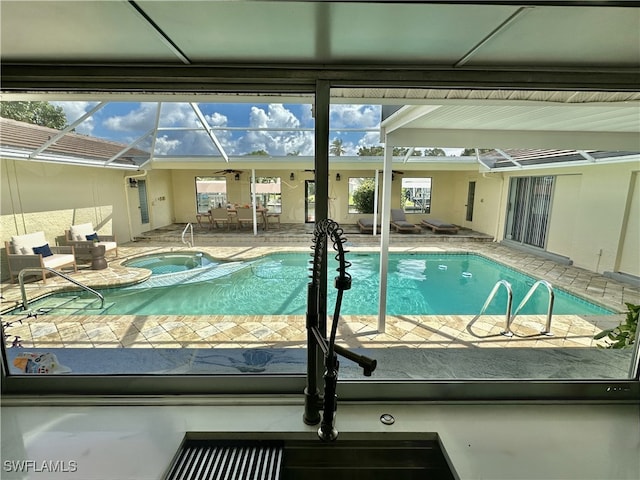 view of swimming pool with glass enclosure, an in ground hot tub, and a patio