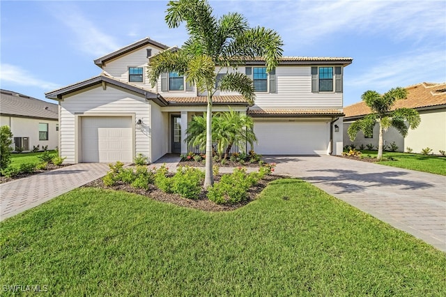 view of front of property with a garage, a front lawn, and central AC