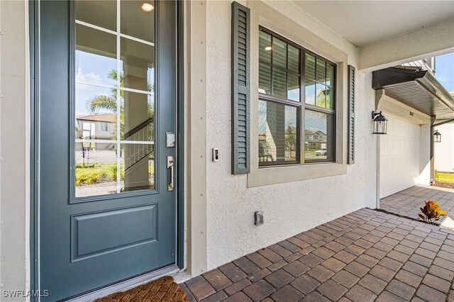 doorway to property featuring a porch and a garage