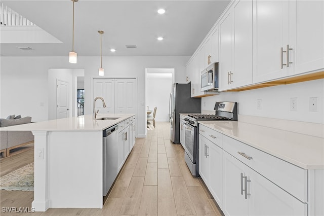 kitchen featuring hanging light fixtures, sink, light hardwood / wood-style flooring, white cabinetry, and appliances with stainless steel finishes