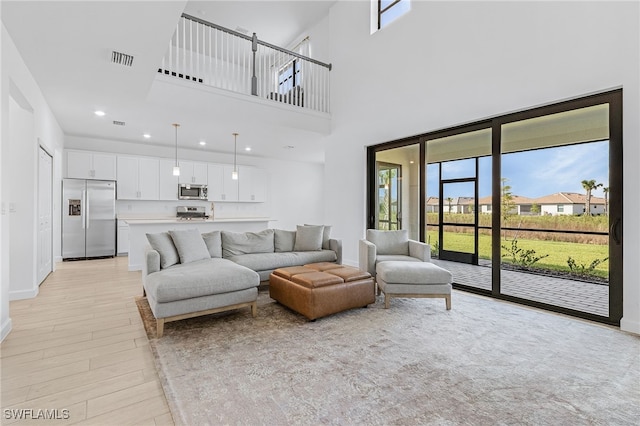 living room with a towering ceiling and light hardwood / wood-style flooring