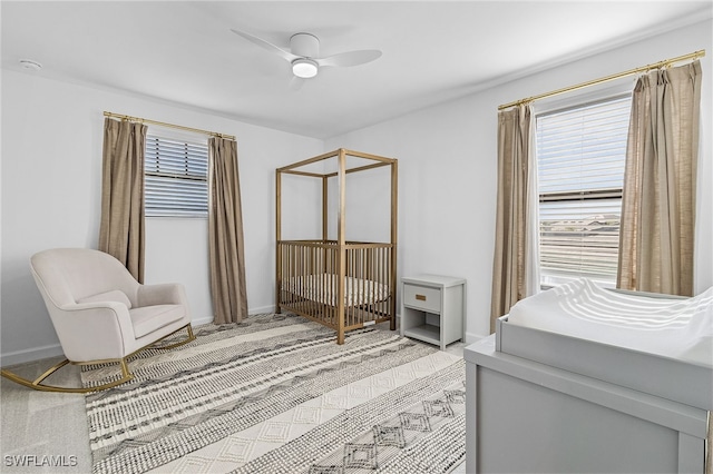 carpeted bedroom with ceiling fan and a crib