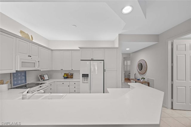 kitchen with white cabinetry, kitchen peninsula, sink, white appliances, and light tile patterned floors