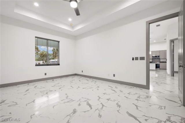 spare room with a tray ceiling and ceiling fan