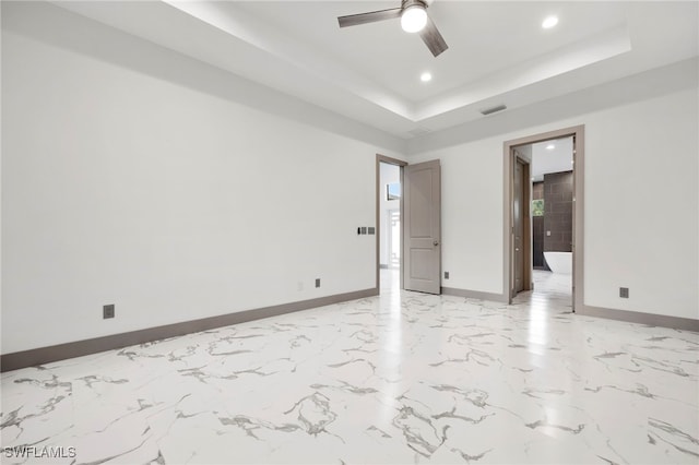 unfurnished room with ceiling fan and a tray ceiling