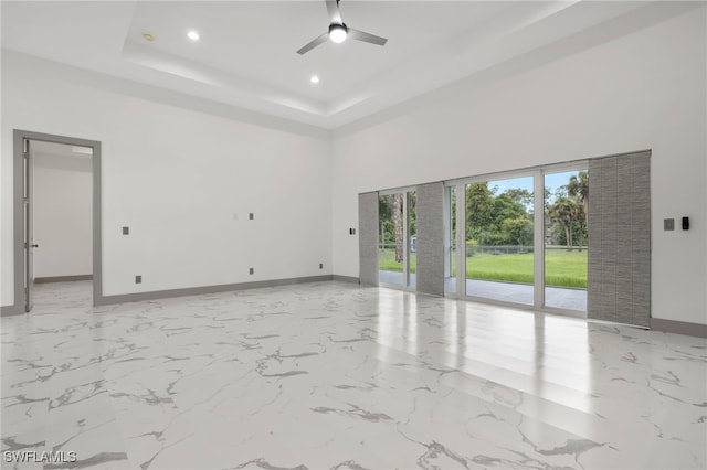 empty room featuring ceiling fan and a raised ceiling