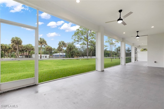 unfurnished sunroom featuring ceiling fan and a wealth of natural light