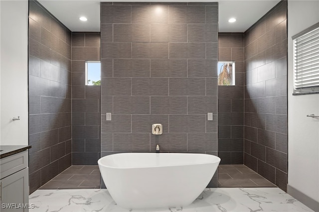 bathroom with vanity, plus walk in shower, tile walls, and a wealth of natural light