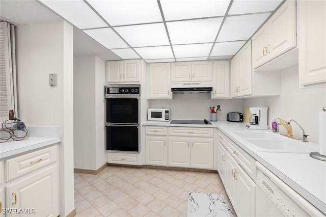 kitchen featuring black appliances, sink, a paneled ceiling, and white cabinets