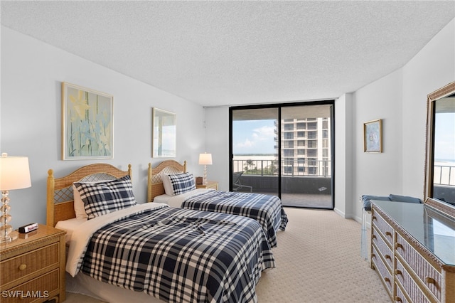 carpeted bedroom with access to outside, a textured ceiling, and a wall of windows