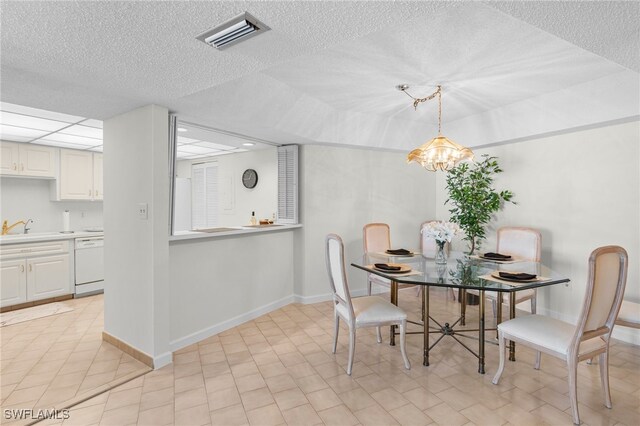 tiled dining area featuring an inviting chandelier, a textured ceiling, and sink