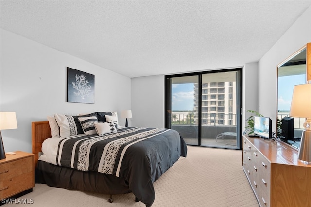 bedroom featuring a textured ceiling, access to outside, light carpet, and expansive windows