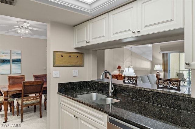 kitchen featuring dark stone counters, sink, white cabinetry, crown molding, and ceiling fan