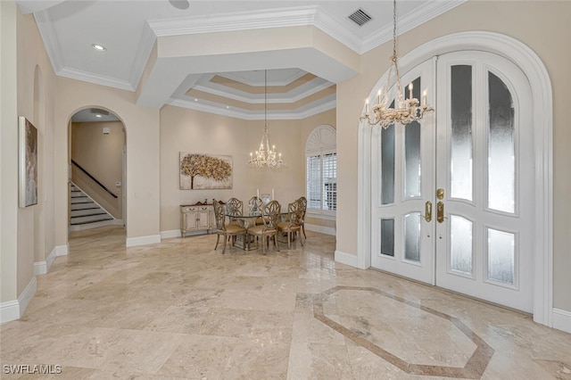 entrance foyer with a chandelier, plenty of natural light, french doors, and crown molding