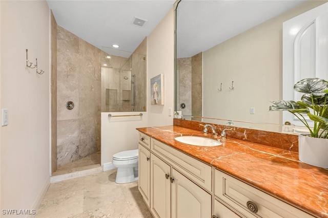 bathroom with a tile shower, vanity, and toilet