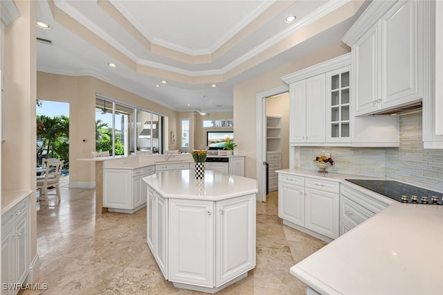 kitchen with white cabinets, crown molding, a kitchen island, decorative backsplash, and black electric cooktop