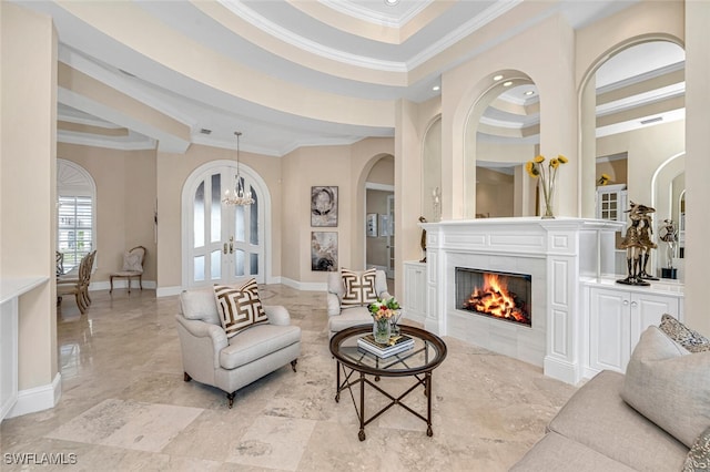 living room with a towering ceiling, a tiled fireplace, a chandelier, and crown molding