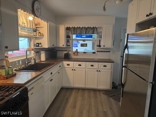 kitchen featuring white cabinets, white dishwasher, sink, stainless steel refrigerator, and hardwood / wood-style floors