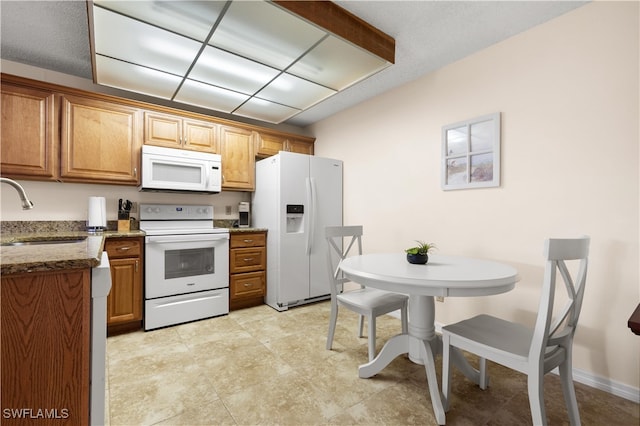 kitchen with dark stone counters, white appliances, and sink