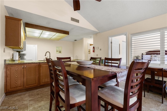 dining space featuring a textured ceiling, lofted ceiling, and sink