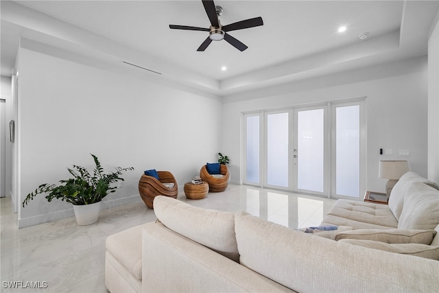 living room with ceiling fan and a raised ceiling