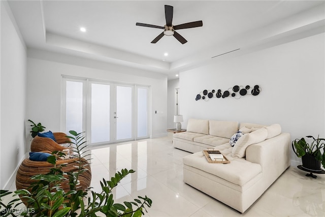 living room with a raised ceiling and ceiling fan