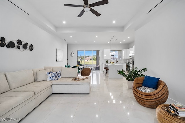 living room featuring ceiling fan and a raised ceiling