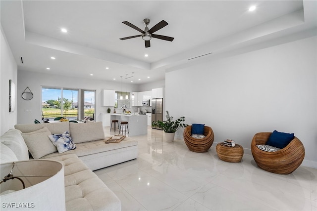 living room with ceiling fan and a tray ceiling