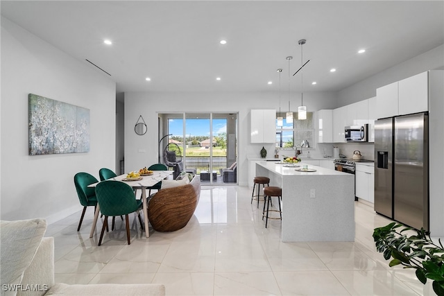 kitchen featuring a kitchen island, pendant lighting, stainless steel appliances, and white cabinets