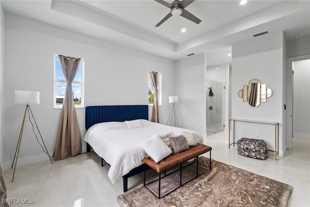 bedroom with ceiling fan, a raised ceiling, and ensuite bath