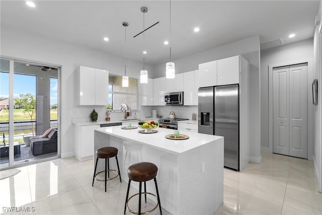 kitchen featuring white cabinets, appliances with stainless steel finishes, pendant lighting, and a center island