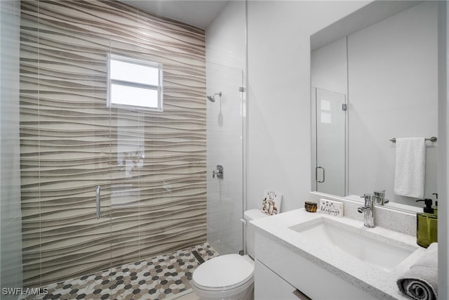 bathroom featuring vanity, a shower with shower door, and toilet