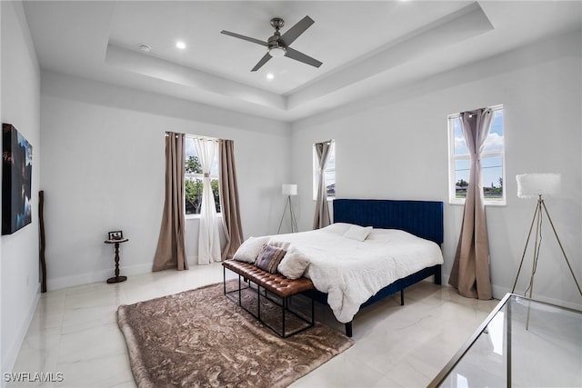 bedroom with ceiling fan and a raised ceiling