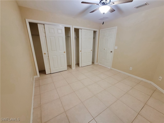 unfurnished bedroom featuring multiple closets, ceiling fan, and light tile patterned flooring