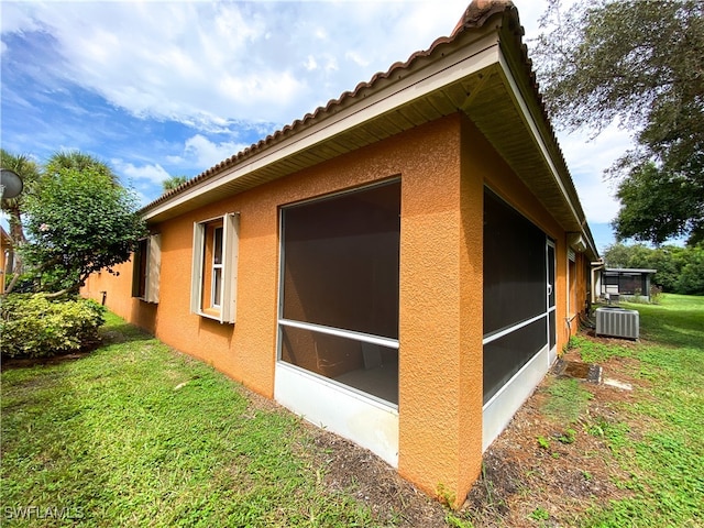 view of side of home with a sunroom, a yard, and central air condition unit