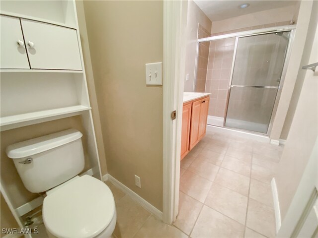 bathroom with tile patterned flooring, a shower with shower door, vanity, and toilet