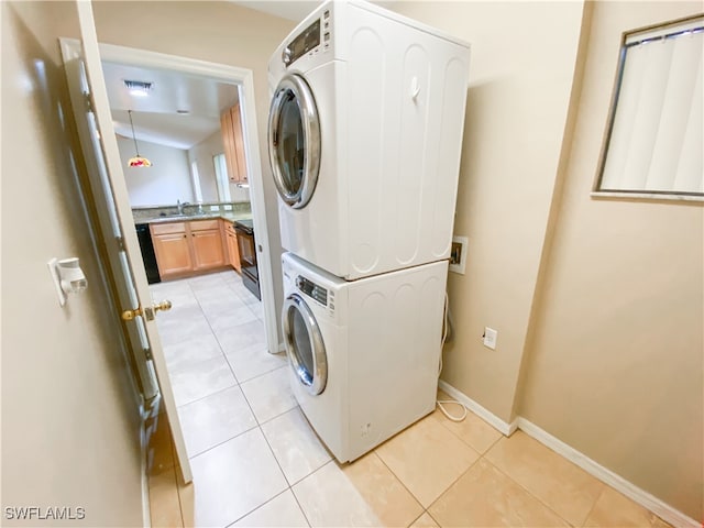 washroom with stacked washer and dryer, sink, and light tile patterned floors