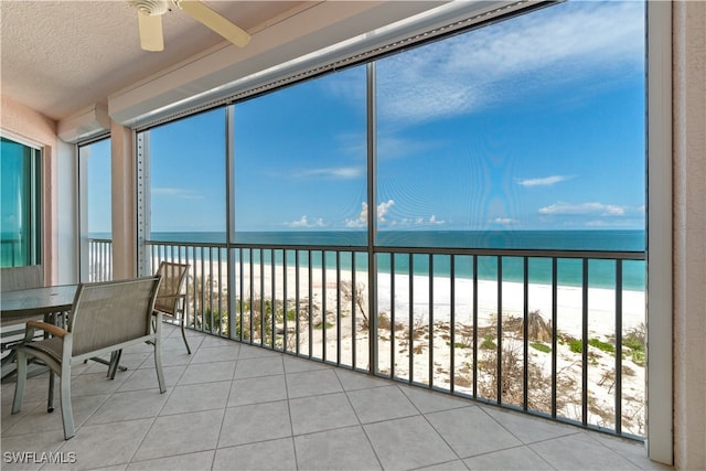 sunroom / solarium featuring a water view, a beach view, and ceiling fan