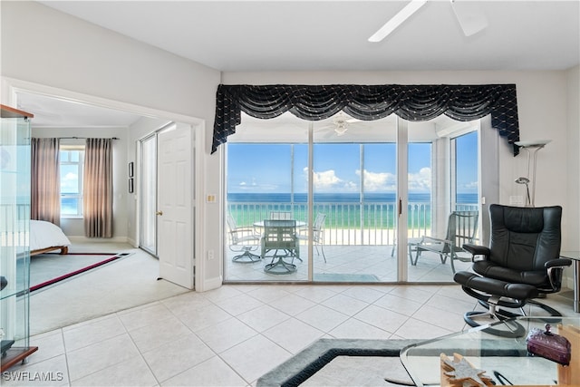 living room with ceiling fan, a water view, and tile patterned floors