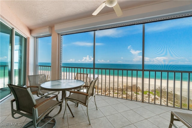 sunroom featuring a view of the beach, a water view, and ceiling fan