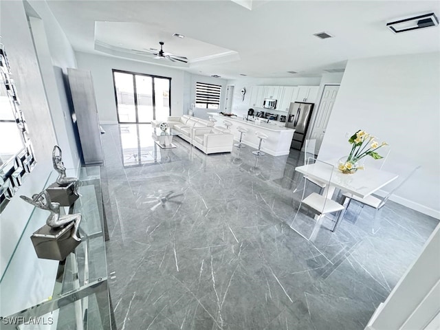 unfurnished living room featuring a tray ceiling and ceiling fan