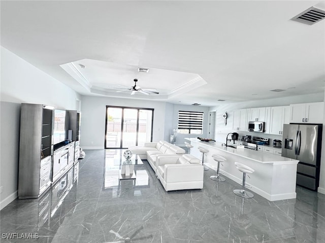 living room with crown molding, a tray ceiling, and ceiling fan