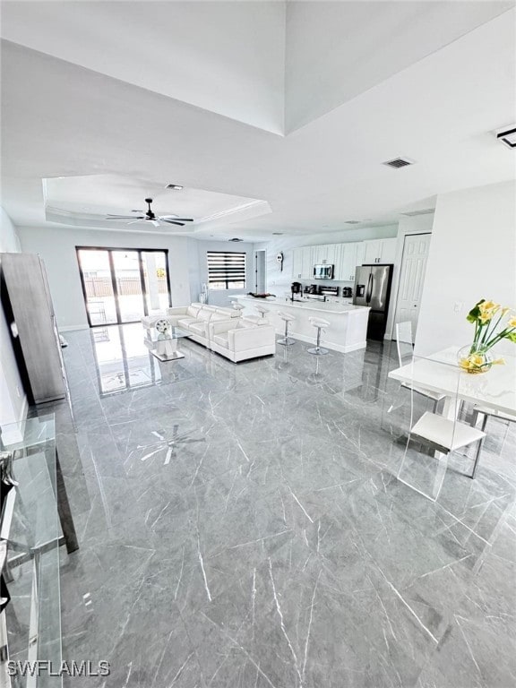 interior space featuring ceiling fan and a tray ceiling