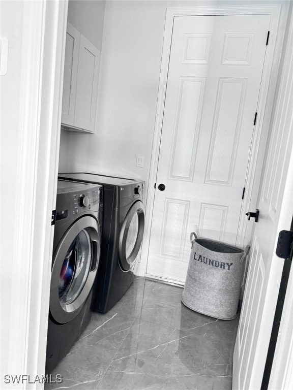 laundry room featuring washer and clothes dryer and cabinets