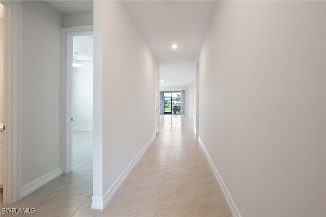 corridor featuring recessed lighting, baseboards, and light tile patterned floors