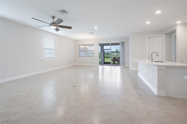 unfurnished living room with ceiling fan with notable chandelier, light tile patterned floors, and sink