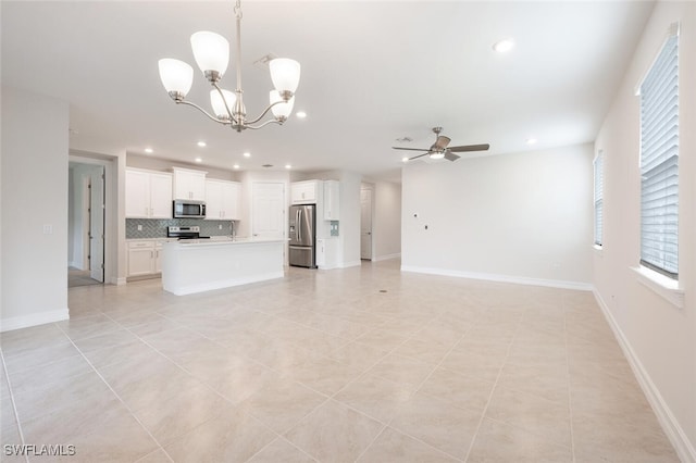 unfurnished living room with ceiling fan with notable chandelier and light tile patterned floors