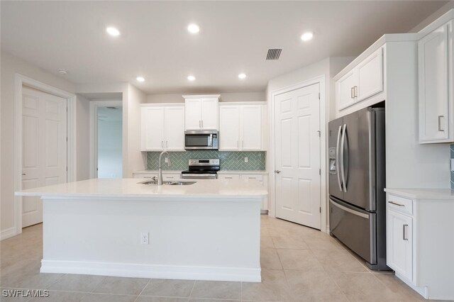 kitchen with a center island with sink, sink, light tile patterned floors, white cabinetry, and stainless steel appliances