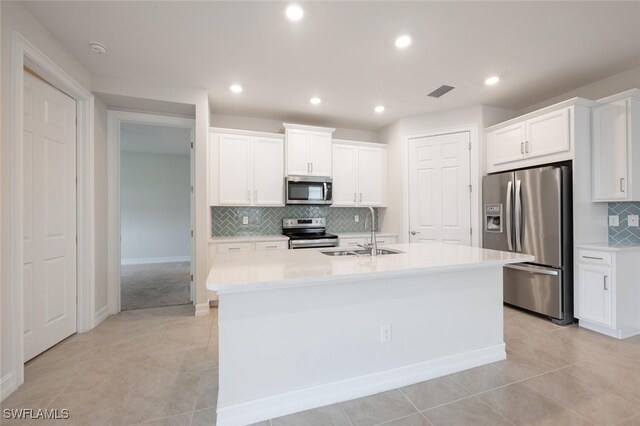 kitchen with appliances with stainless steel finishes, an island with sink, white cabinetry, and sink