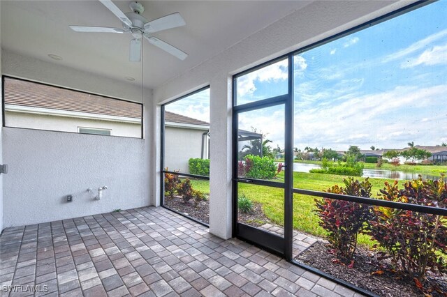 unfurnished sunroom featuring a water view and ceiling fan